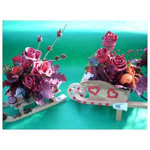 Composizioni di fiori e roselline trattate con cera in piccoli slittini