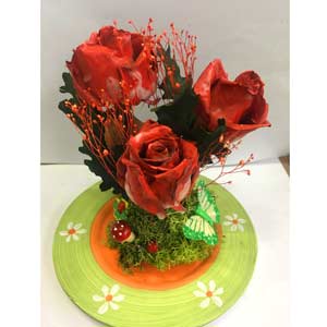 Composizione con rose stabilizzate su piatto con decorazioni
